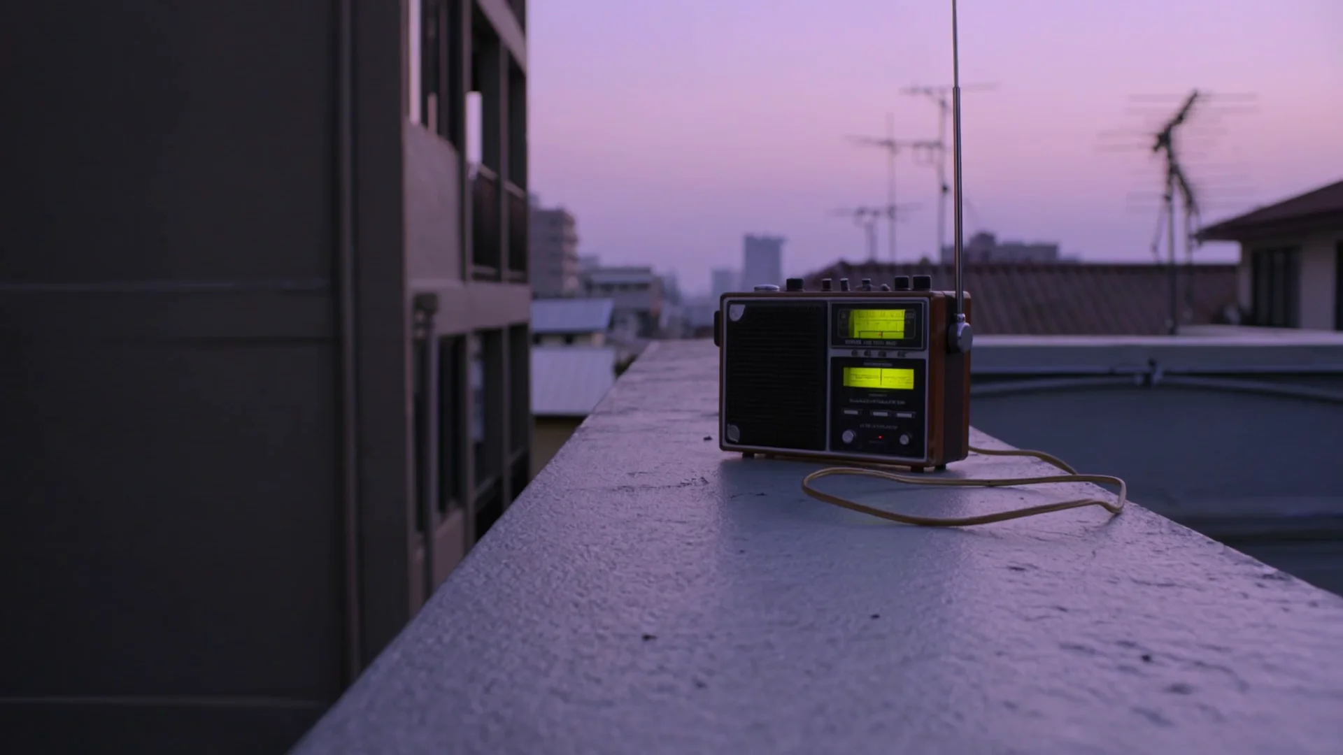 An analog radio above violet city rooftops